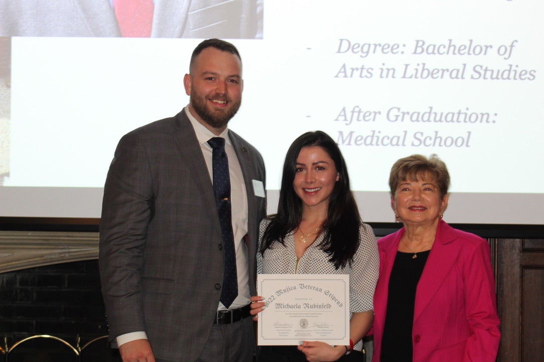 3 people with one holding an award certificate