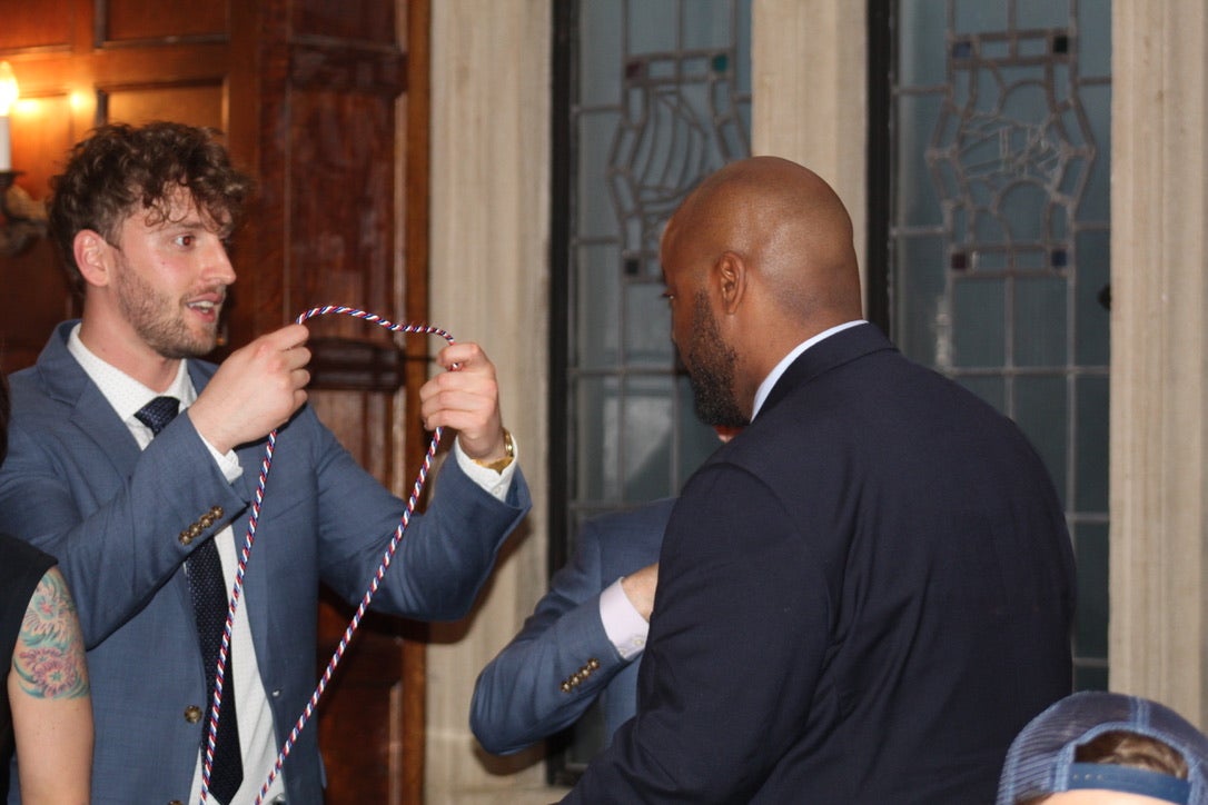 one man putting a graduation cord on another