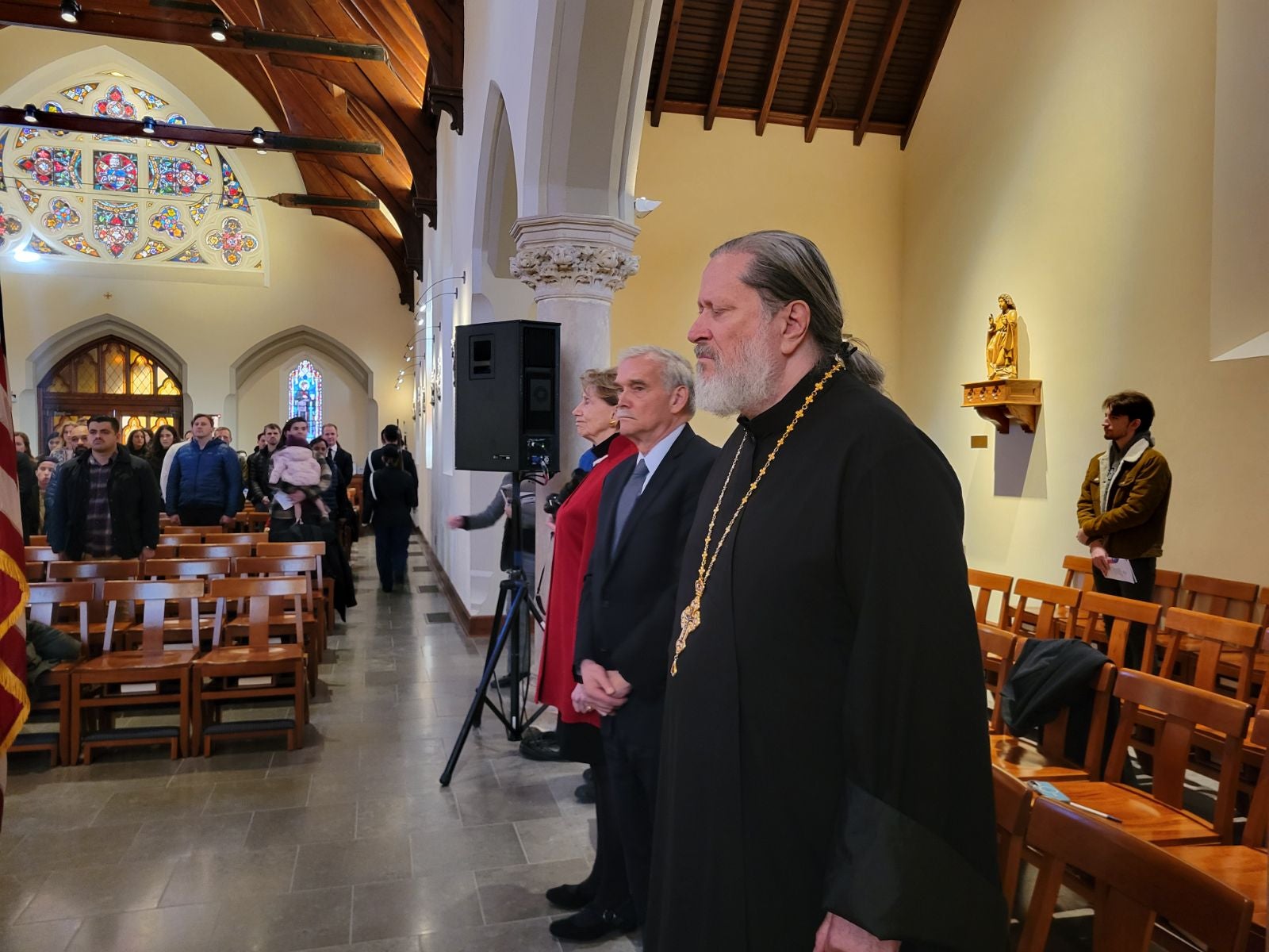 Father Pratt ad other distinguished guests standing at the side of the event space