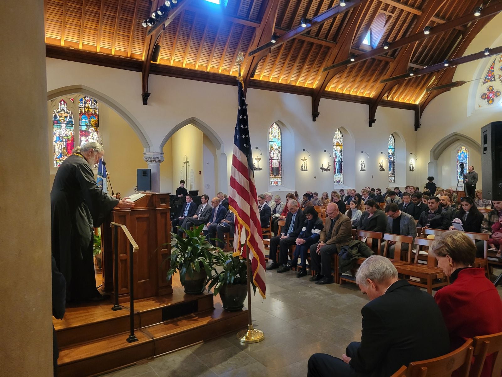 Father Pratt giving the prayer and the audience's heads' bowed
