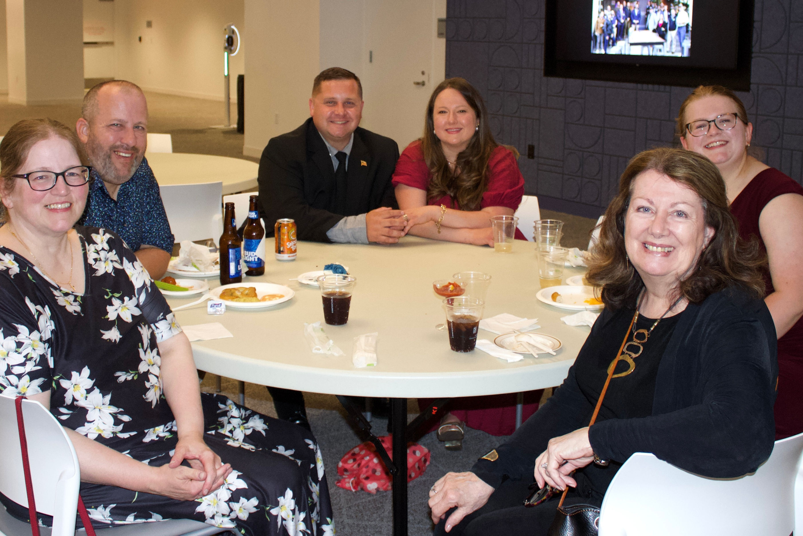 Guests sitting around a white, round table smiling for a photo