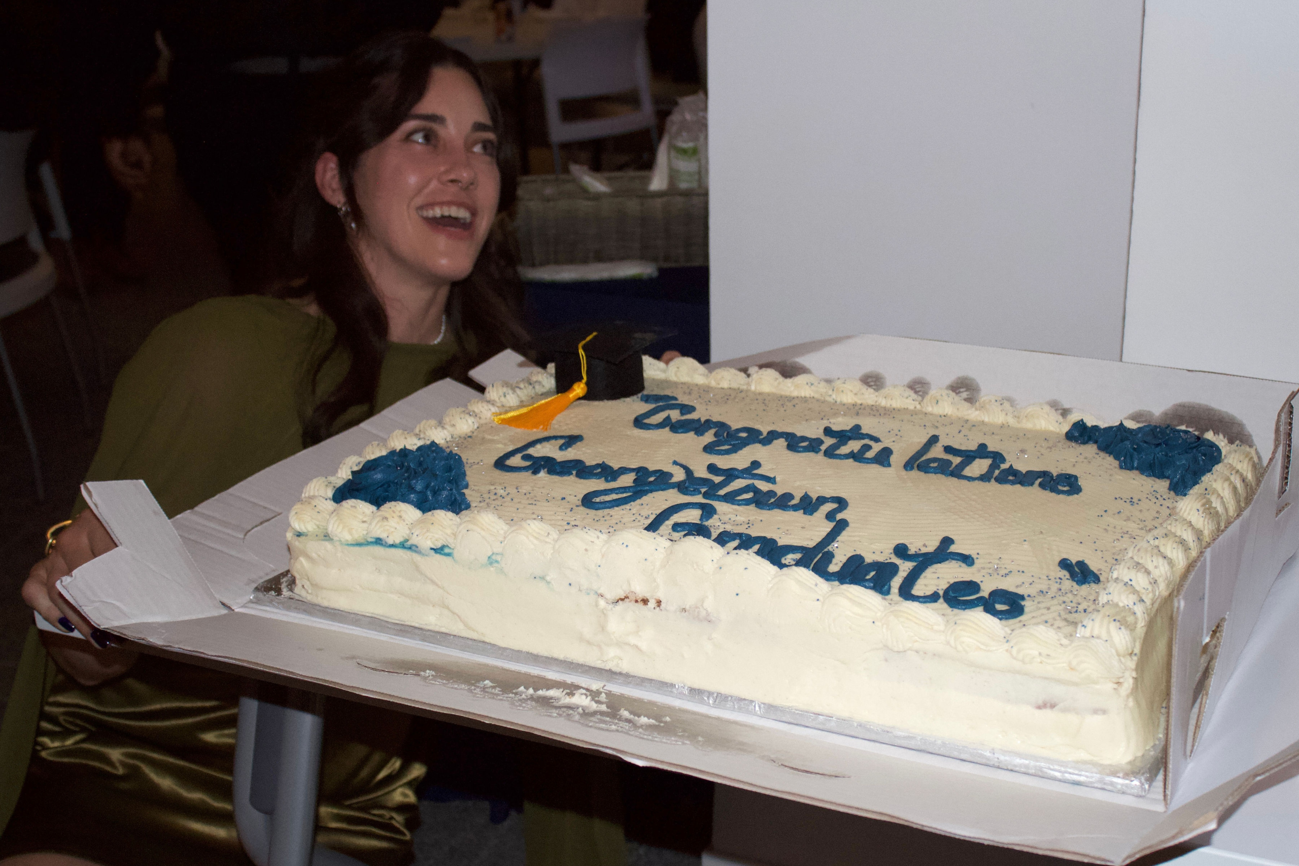 Woman crouched down behind a cake reading 'Congratulations Georgetown graduates'