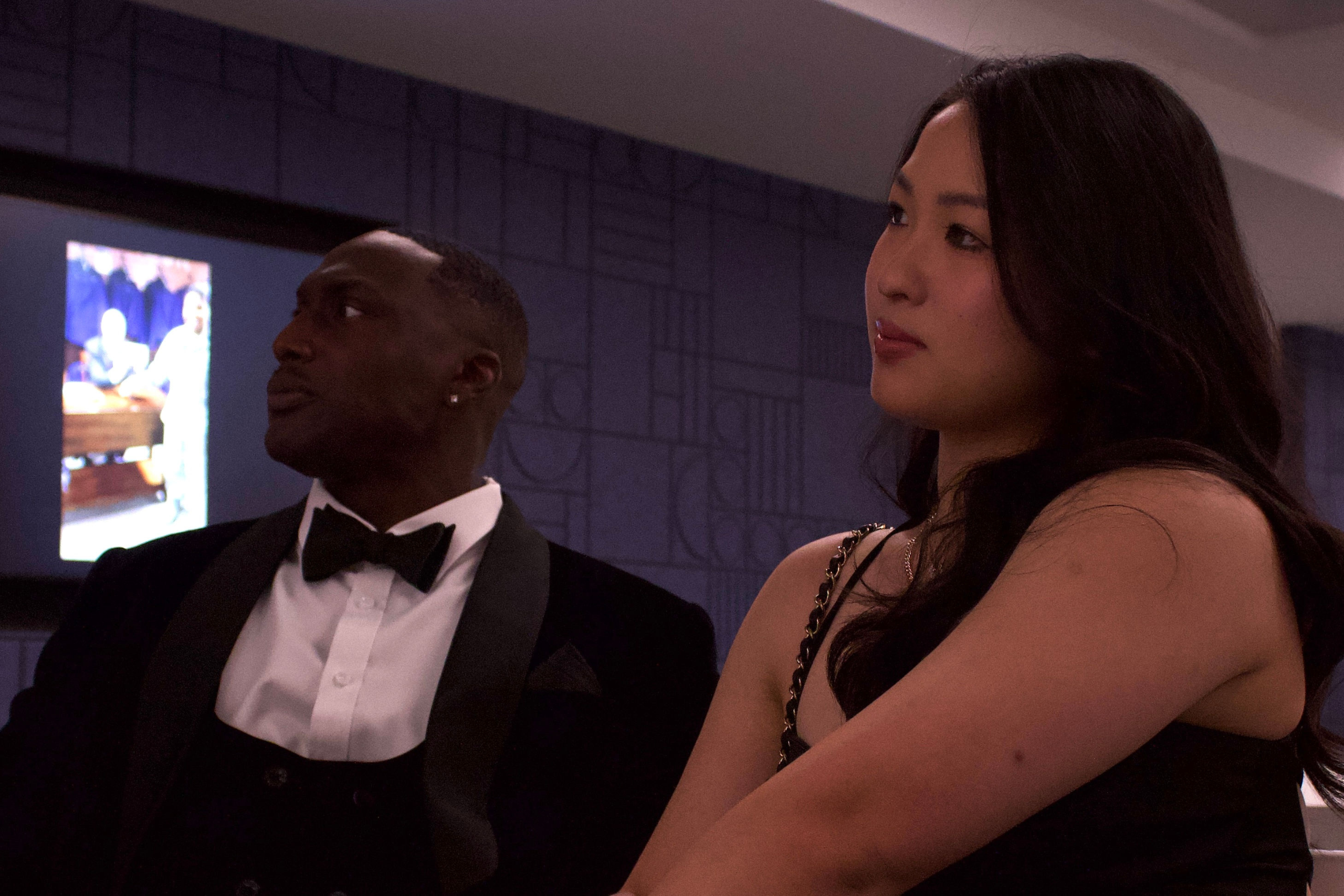 A man and a woman look at someone presenting offscreen