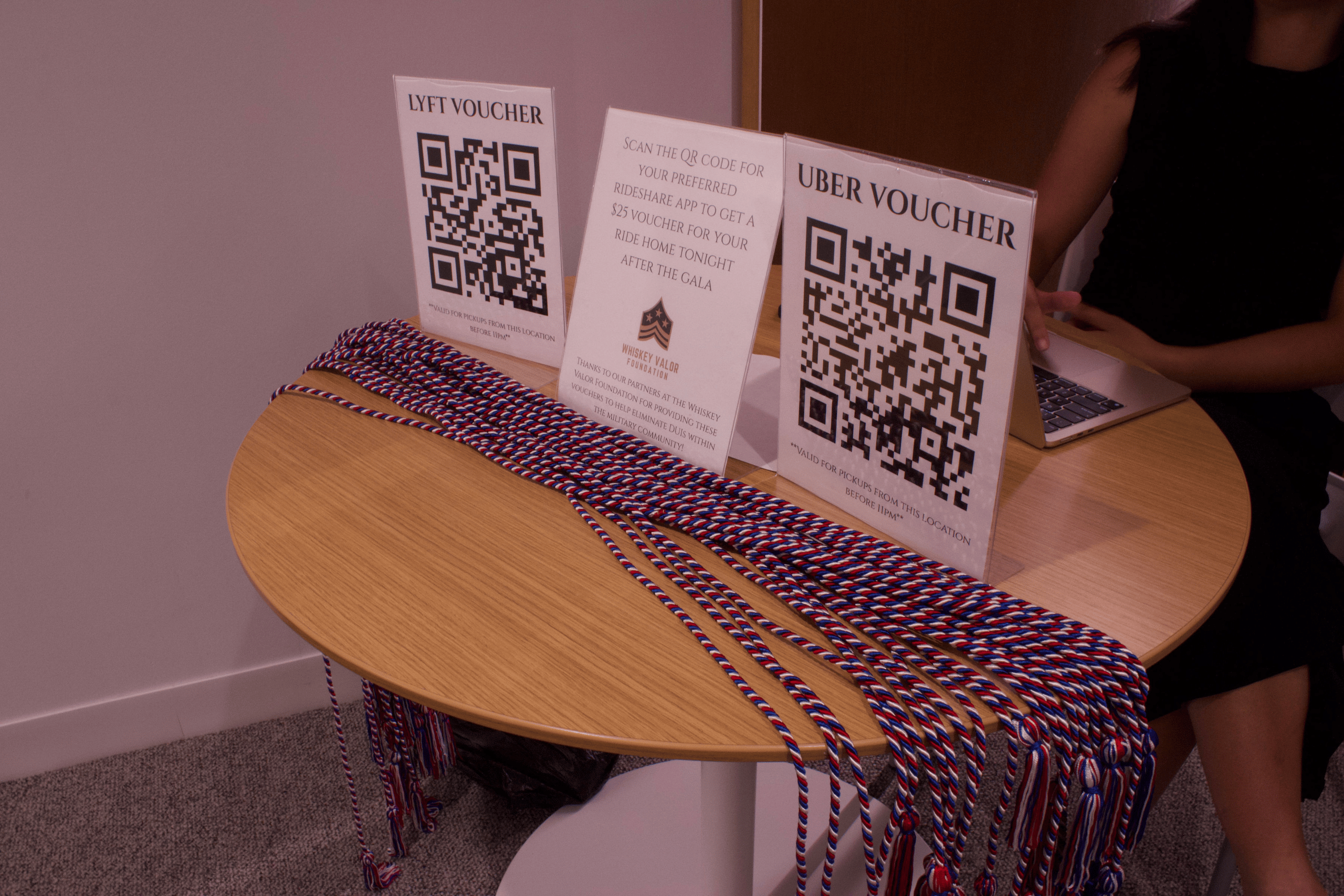 Graduation cords and papers with QR codes on a small, round, wood table