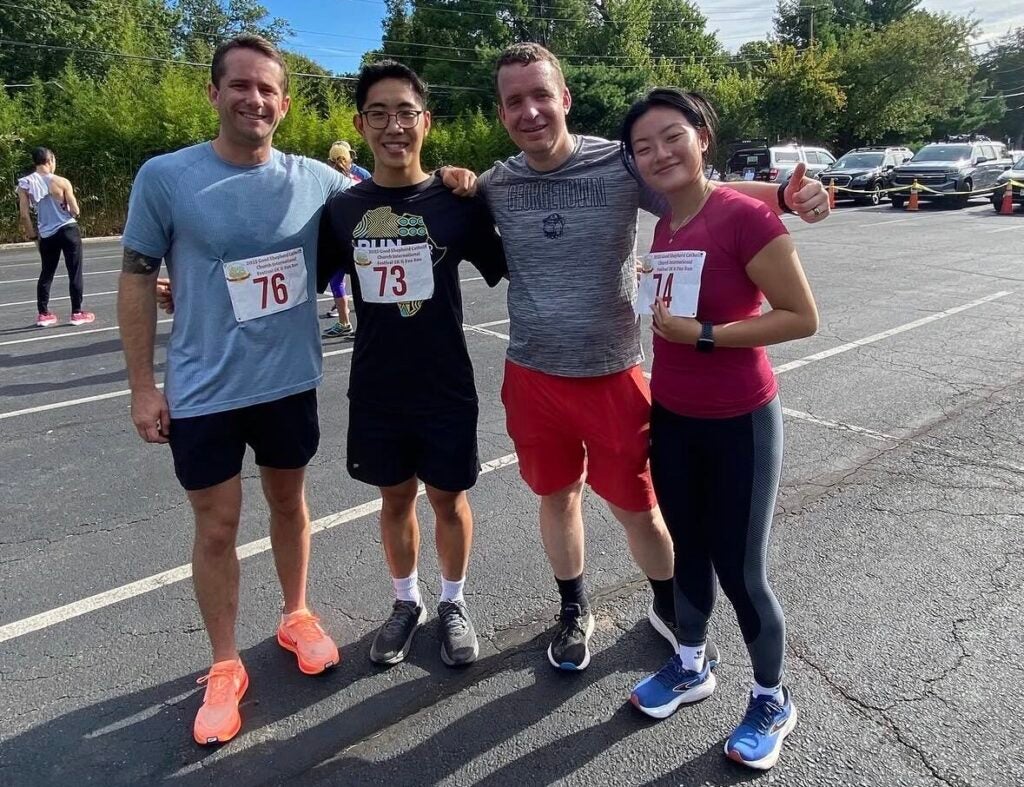 A group of four people posing for a photo after a run, wearing bibs and athletic gear