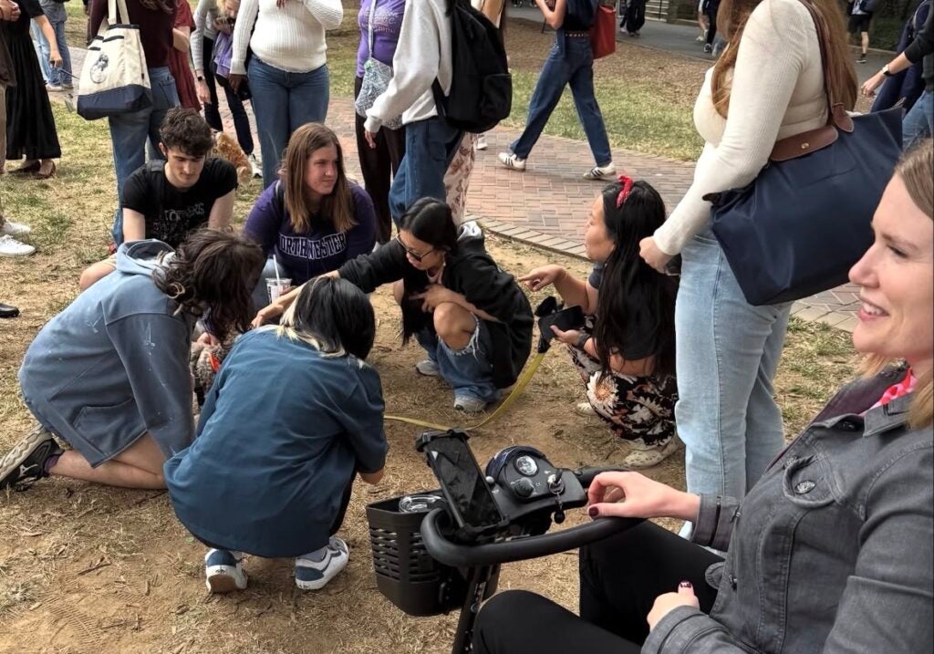 A group of people and a woman in a wheelchair crouched around a dog