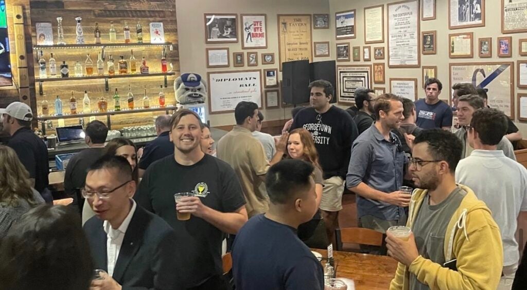 Several people mingling in a bar around tables