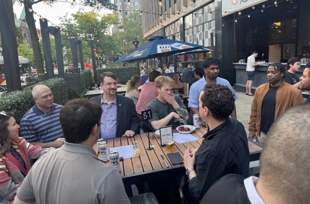 A group of men around an outdoor table at a restaurant eating and talking