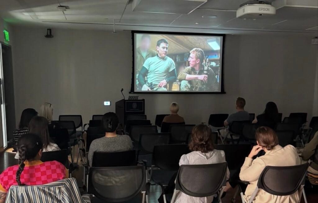 People sitting in chairs watching a movie at the front of the room