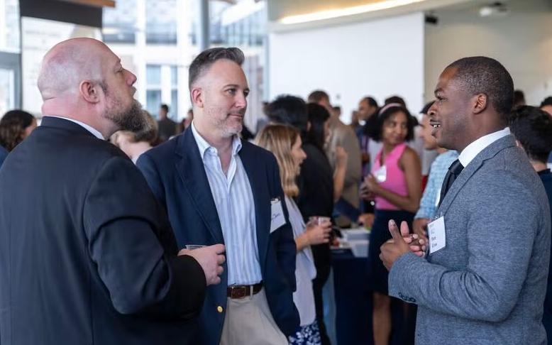 Three men standing and talking at a networking event