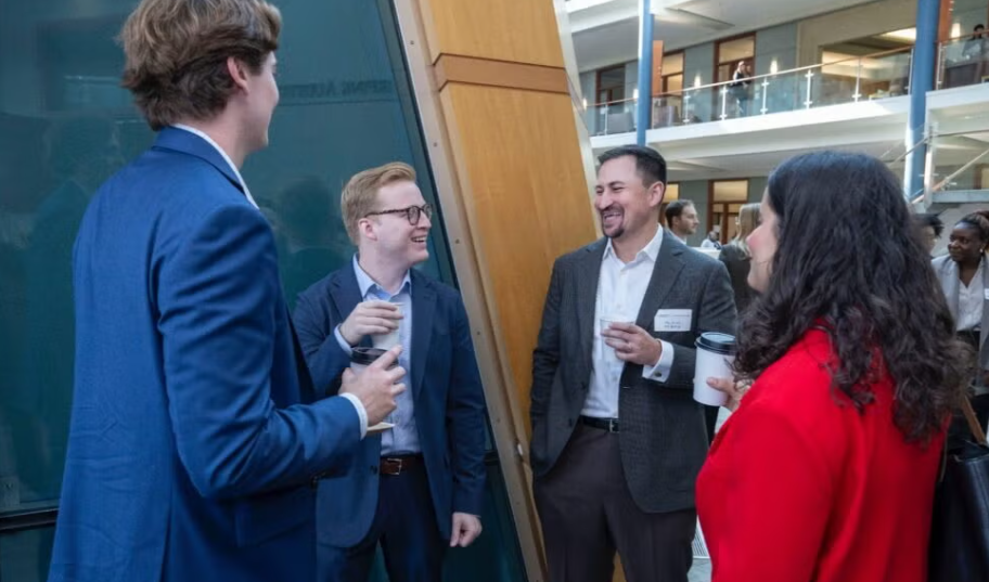 Three men and one woman standing in a group talking at a reception