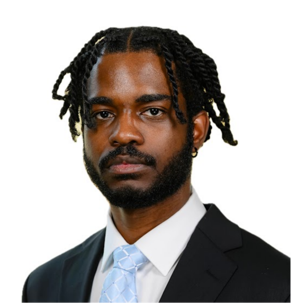 An African American man with medium length black hair wearing a black suit and blue tie