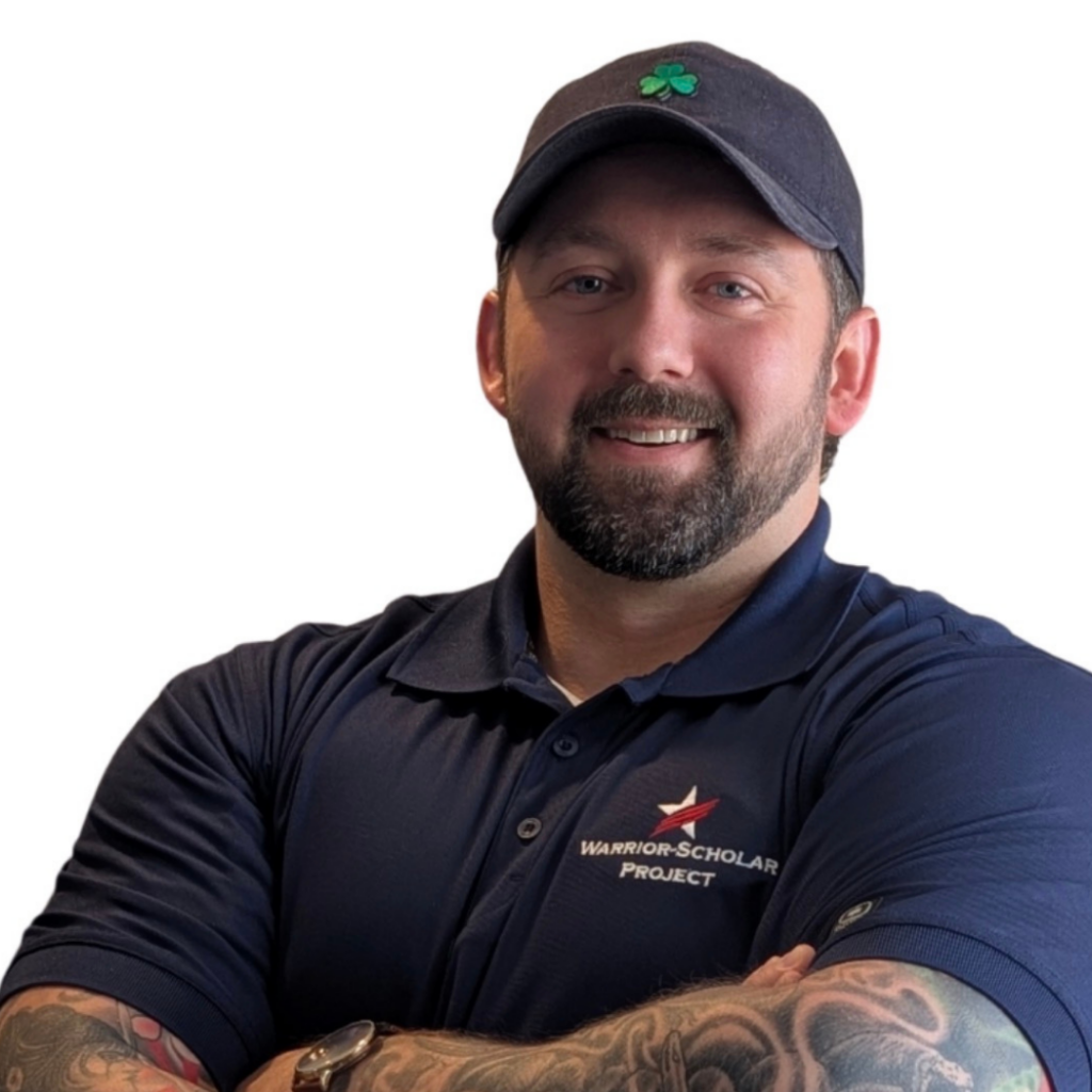 White man with a black beard and a gray baseball cap wearing a dark blue polo