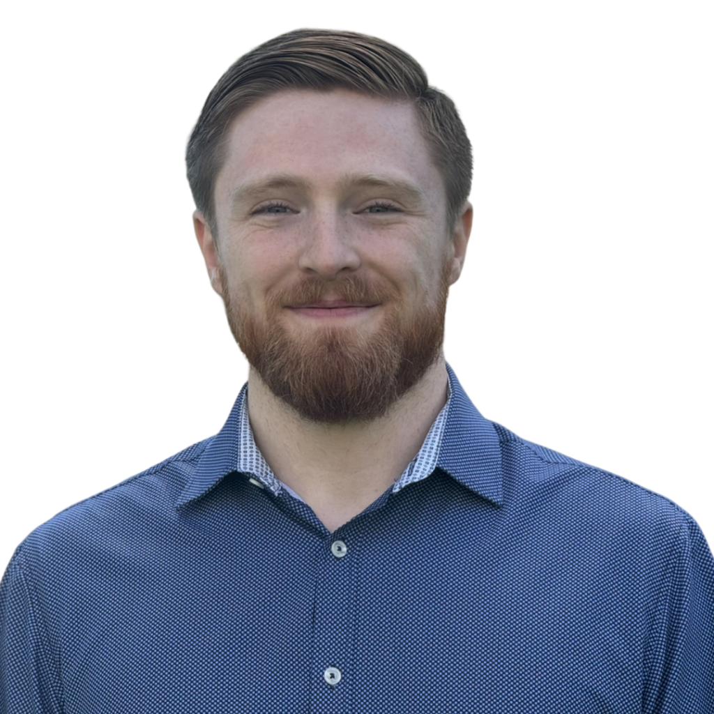 A white man with short red hair and a beard wearing a blue button down shirt
