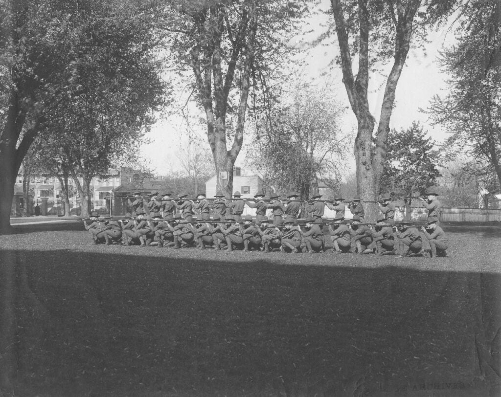 Cadets in uniform in two lines facing off camera with long rifles 
