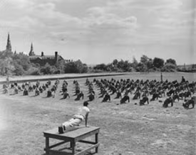 Students working out in a block formation in the grass with Healy hall in the background