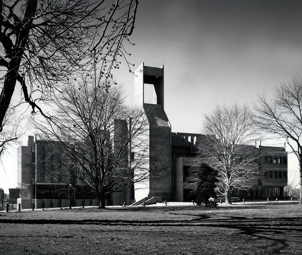 A brutalist style library building with barren trees in front